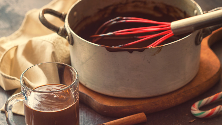 Pot of hot chocolate next to two cups