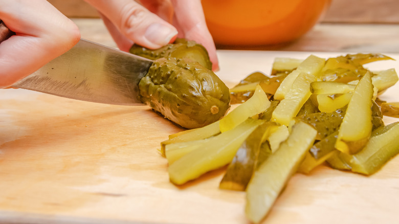 person chopping pickles on cutting board