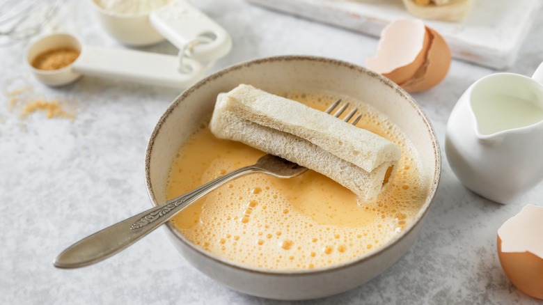 Dipping bread in custard french toast batter