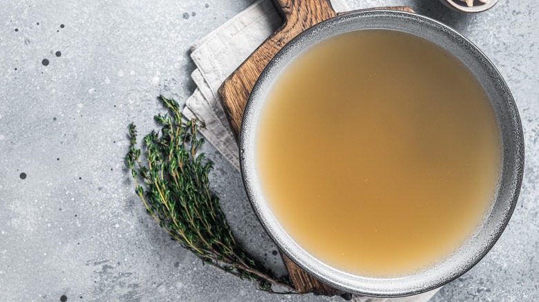 Overhead of chicken broth in a bowl on a gray countertop