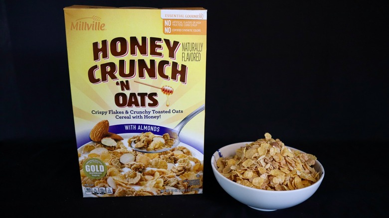 Box and bowl of Millville Honey Crunch 'n Oats with Almonds on black background