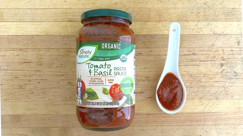 A jar of Simply Nature tomato and basil pasta sauce next to a white spoon with sauce