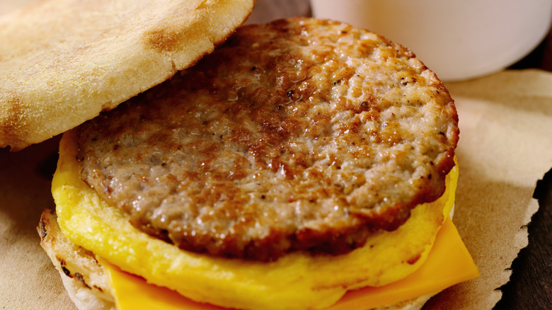 Toasted English muffin with sausage patty, egg patty and slice of American cheese