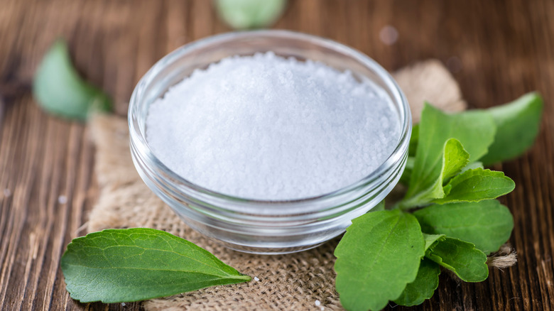 bowl of stevia on wooden table with leaves