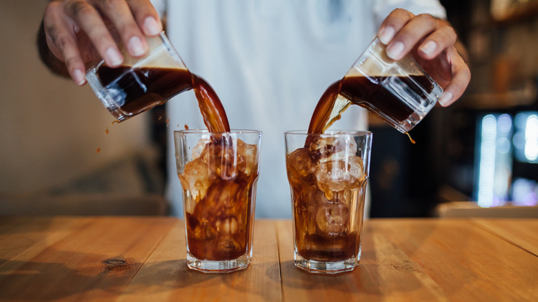 Hands pouring two glasses of cold brew