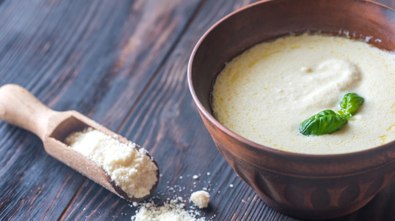 Bowl of alfredo sauce next to parmesan