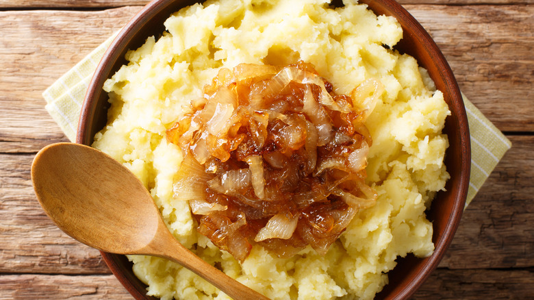 Mashed potato garnished with caramelized onion in bowl