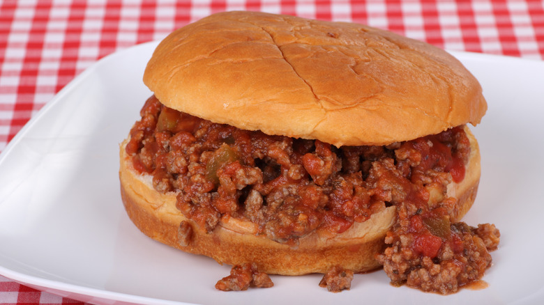 Sloppy Joe sandwich on white plate and checkered tablecloth