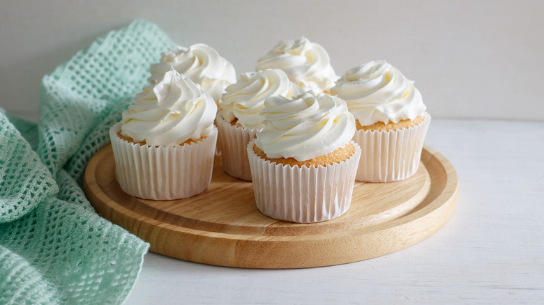 Vanilla cupcakes with vanilla frosting on wood tray