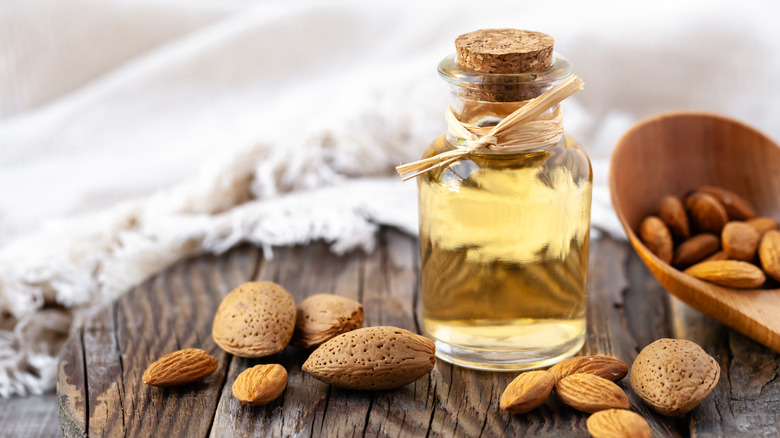 Bottle of extract with almonds on wood surface