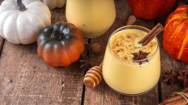 glasses of eggnog with cinnamon sticks and pumpkin decor