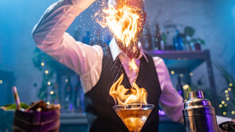 Cocktail waiter preparing drink with open flame