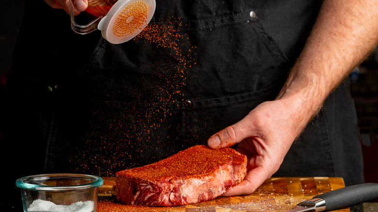 Man sprinkling spice blend on a steak