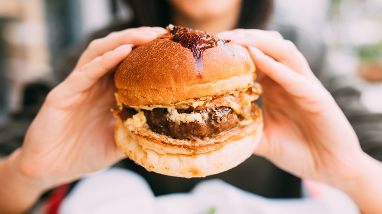 woman's hands holding burger