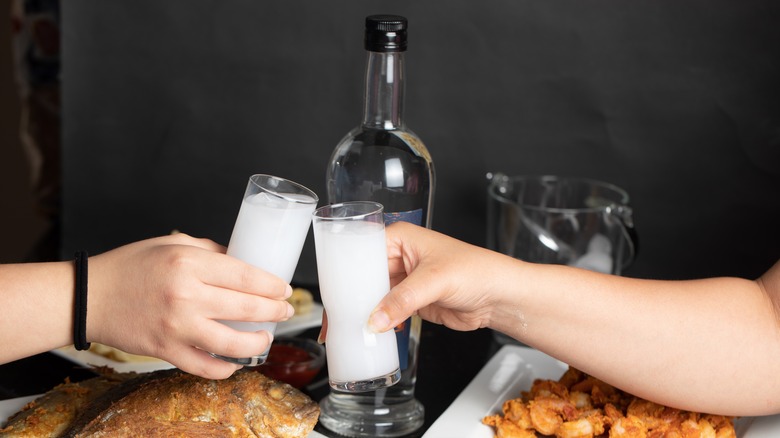 two people toasting glasses of arak 