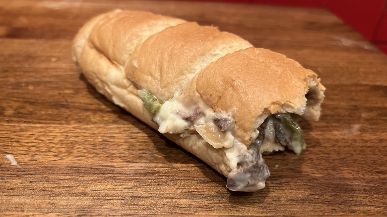 bitten cheesesteak on wooden table