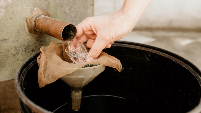 Moonshine pouring from boiler into shot glass