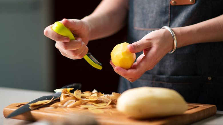 peeling a potato on cutting board