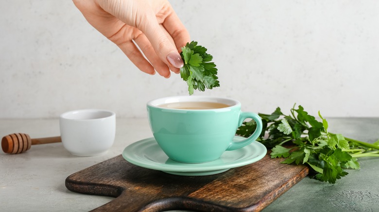 Person preparing hot tea with parsley