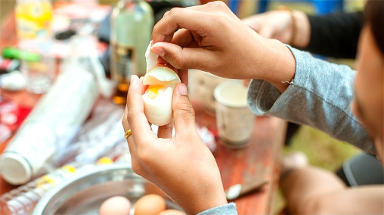 Hand peeling hard-boiled egg outside