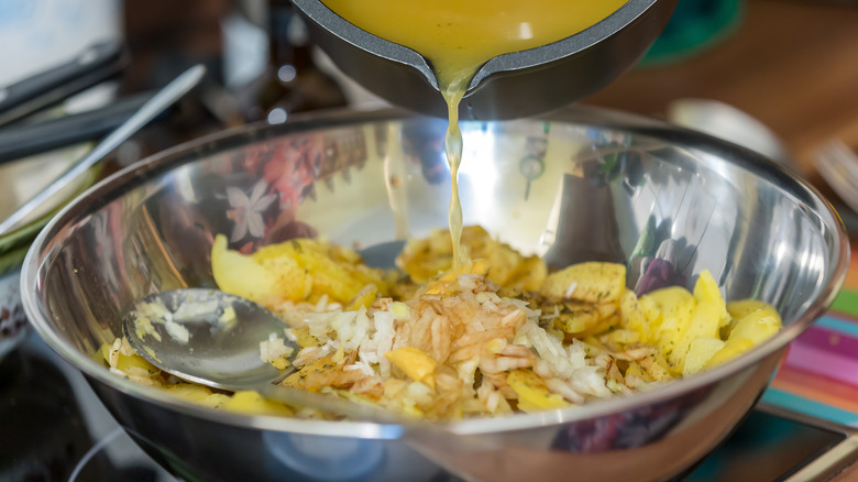 Broth pouring into a bowl for potato salad