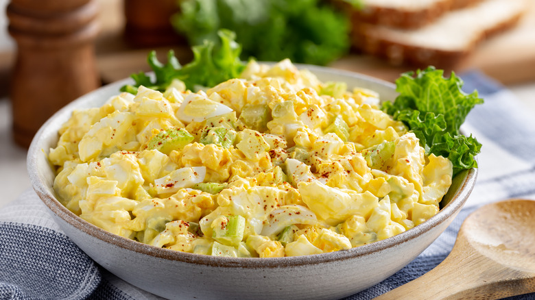 Egg salad in a bowl with green pieces of celery/avocado