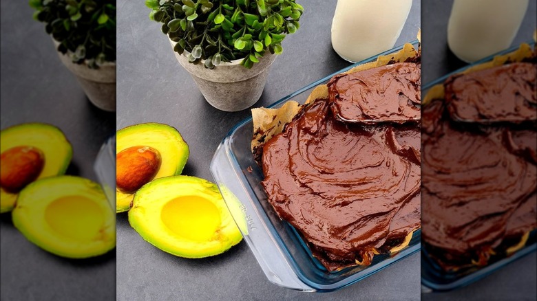 Chocolate frosted brownies and avocadoes on gray counter