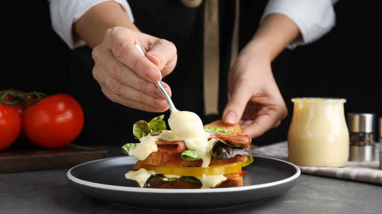 Person putting mayonnaise on sandwich