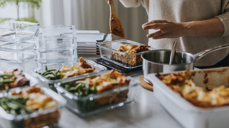 Person prepping individual meals with lasagna in storage containers