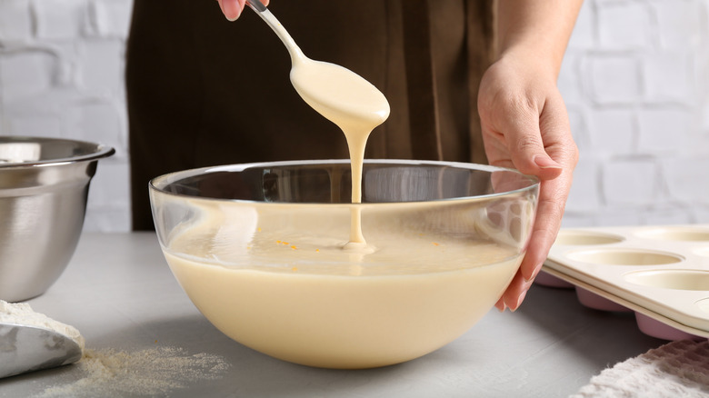 Hand scooping cake batter with spoon