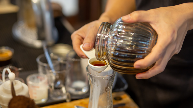 Person pouring honey into measuring spoon