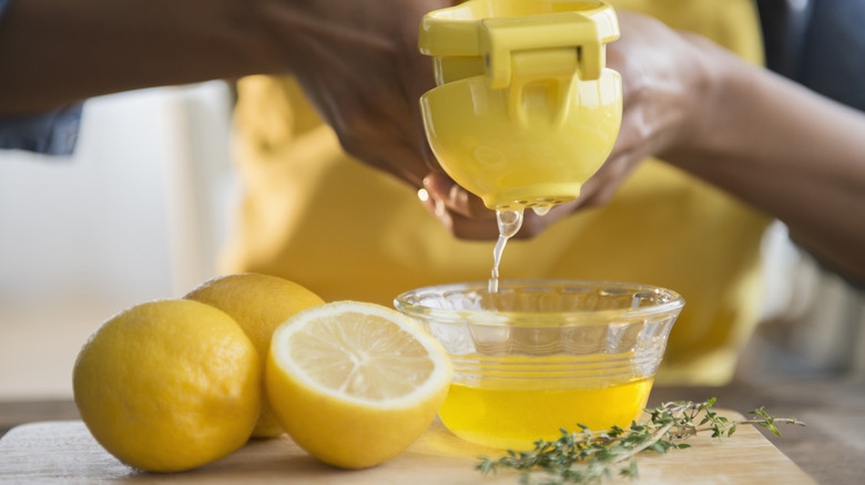 Lemons being squeezed into little glass bowl