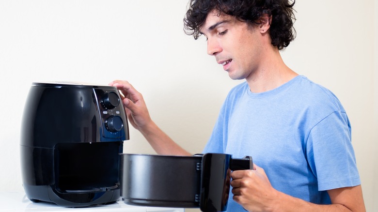 man checking air frying progress