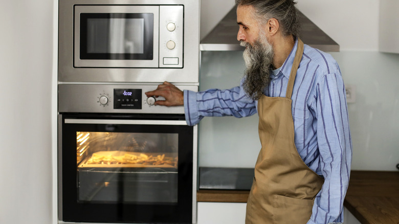 man adjusting oven temperature