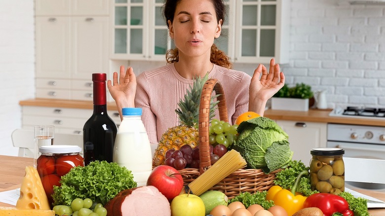 Woman sitting behind mountain of groceries