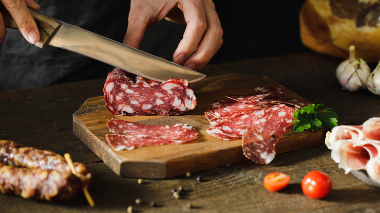 Cutting salami on wooden board