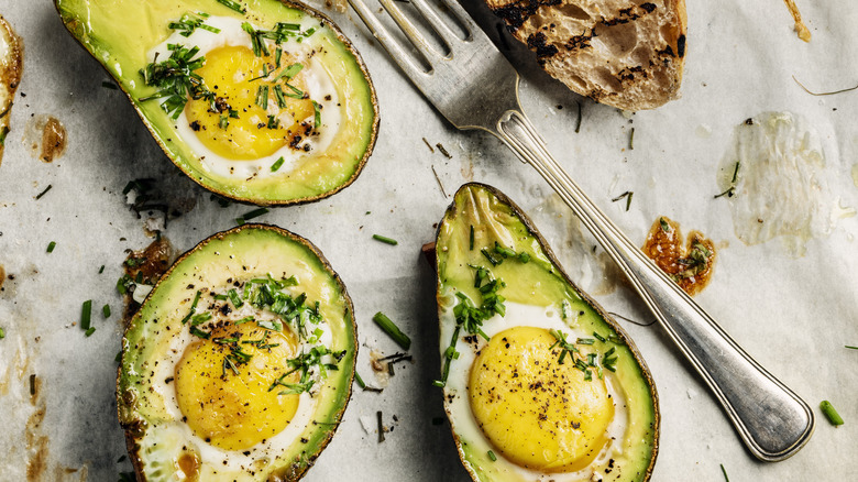 Baked avocado eggs with fork and bread