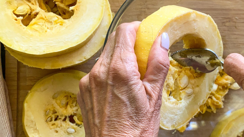 hand scraping seeds out of squash