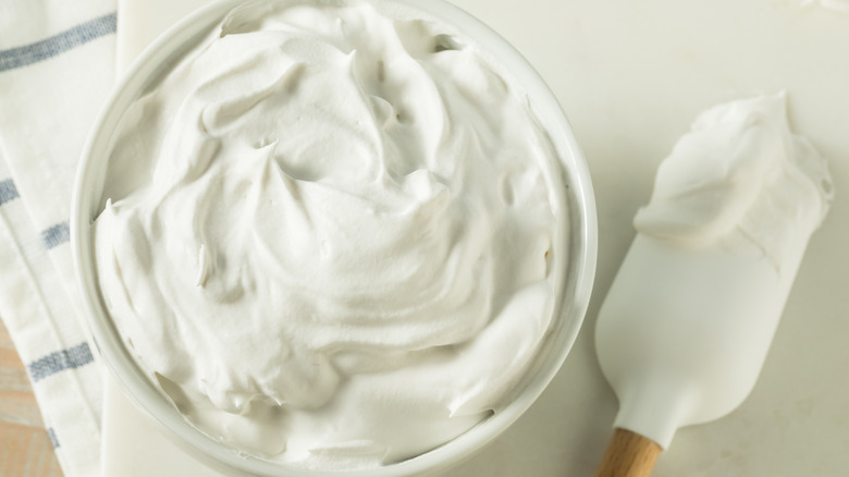 bowl of white frosting next to spatula