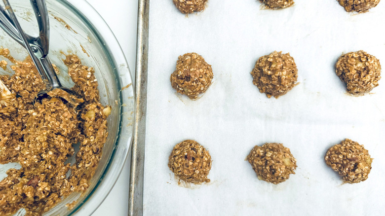 unbaked cookies on baking sheet next to bowl of dough