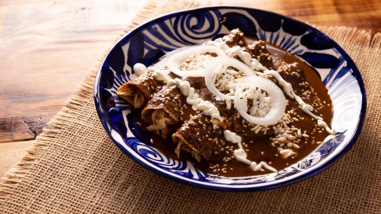 Enchilada mole on blue plate atop wooden table