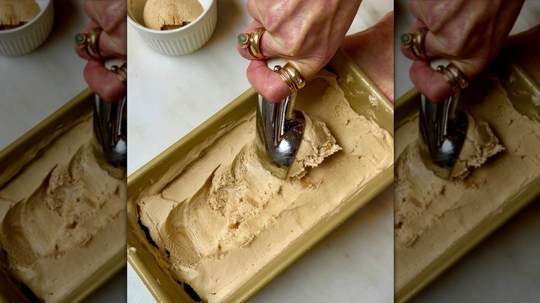 Hand with rings scooping ice cream from a pan