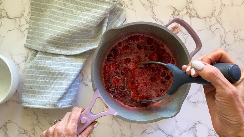 cranberries in pot with with potato masher