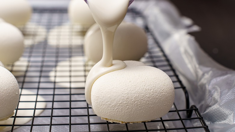 cake base being poured with white mirror glaze