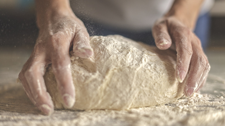 Person kneading pizza dough