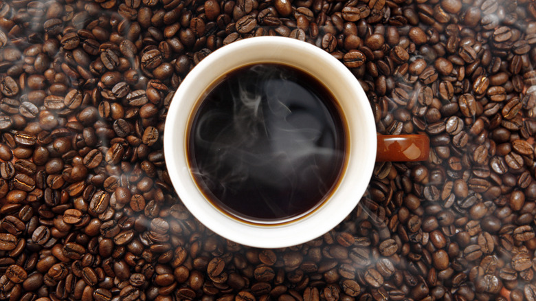 Cup of coffee surrounded  by beans