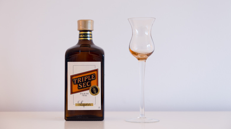A bottle of triple sec and tall tulip glass
