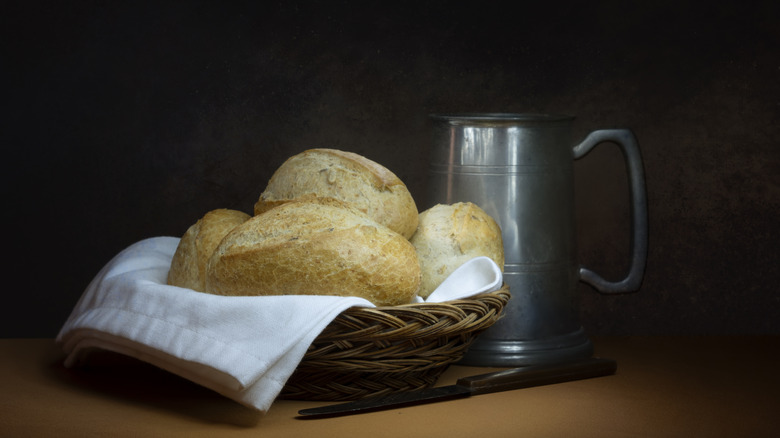 Basket of bread next to a pewter tankard