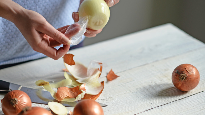 Person removing onion skins