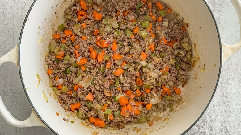 ground beef in dutch oven with mirepoix
